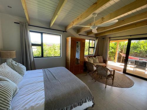 a bedroom with a large bed and a living room at SeaGarden Cottage in Cape St Francis