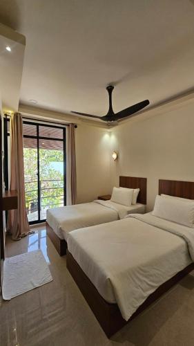 a bedroom with two beds and a ceiling fan at Handhuveli Dhangethi in Dhangethi