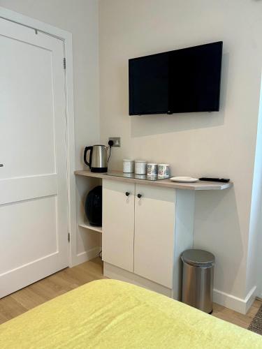 a room with a tv on a wall with a table at Acorns in Hordle