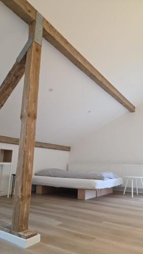 a bed in a white room with wooden beams at Hof Busen Malibu in Mönchengladbach
