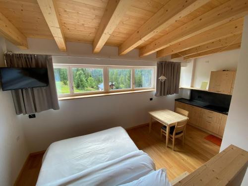 a bedroom with a bed and a table and windows at Hotel Garni Civetta in Selva di Cadore