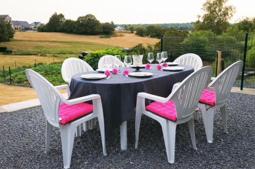 a table with white chairs and a black table with pink seats at Au Chant des Roches Gîte en pierre avec jardin à Cerfontaine in Cerfontaine