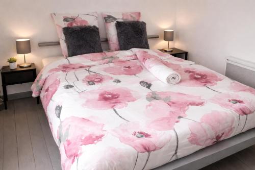 a pink and white bed with pink flowers on it at Au Chant des Roches Gîte en pierre avec jardin à Cerfontaine in Cerfontaine