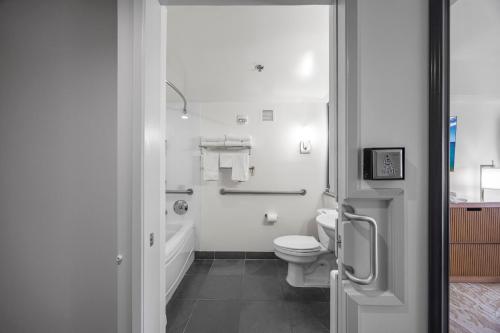 a white bathroom with a toilet and a bath tub at Ala Moana Hotel _ Ocean view with balcony in Honolulu