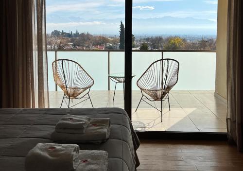 a bedroom with a bed and two chairs and a balcony at Apart Hotel Quijote by DOT Suites in Ciudad Lujan de Cuyo