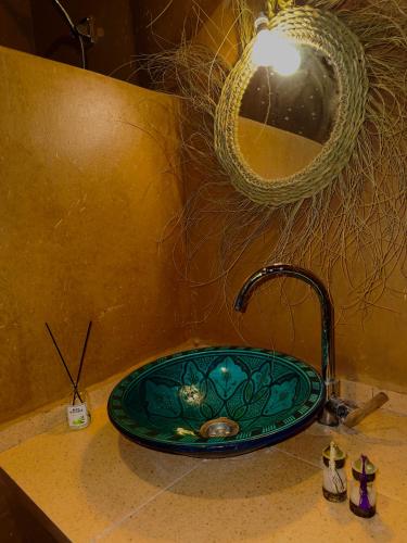 a bathroom sink with a green glass sink at Dar Talmoudi ,Traditional Riad, Local Food, Camel , Desert Excursions in Tagounite