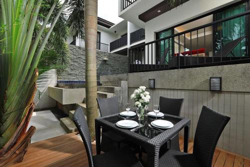 a black table and chairs on a patio with plants at Thaimond Residence by TropicLook Walkable distance to Naiharn beach in Nai Harn Beach