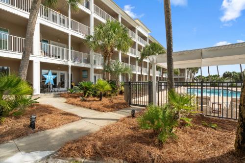 an apartment building with a pool and palm trees at Grand Caribbean East Poolside Palms in Pensacola
