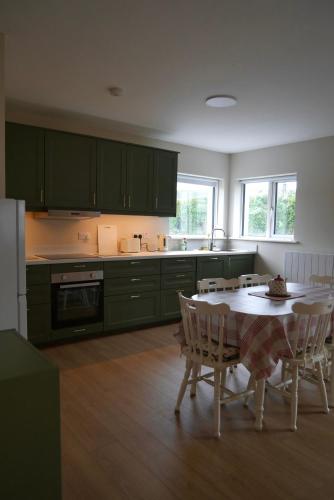 a kitchen with green cabinets and a table with chairs at McGinns Cottage in Kilcormac