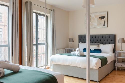 a bedroom with two beds and a large window at Modern 2BR Apartments by Luxus Sleeps 6 City Centre in Belfast