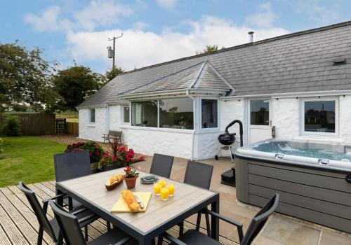 a table and chairs on a patio with a hot tub at Bwthyn y Ddol - a cottage with stunning views in Cardigan