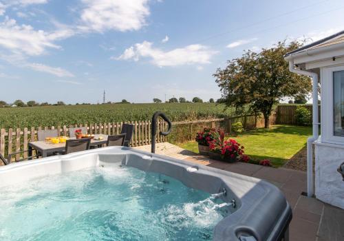 a jacuzzi tub in a yard with a table at Bwthyn y Ddol - a cottage with stunning views in Cardigan