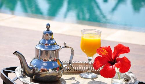 a tea kettle and a glass of orange juice and a flower at Riad Hamdani in Casablanca