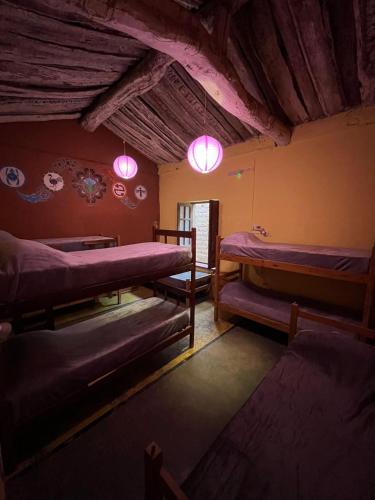 a room with several bunk beds and pink lights at Kamaq Hostel in Humahuaca