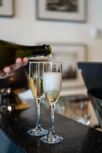 a person pouring champagne into two glasses on a counter at Upsun Hotel in Miami Beach