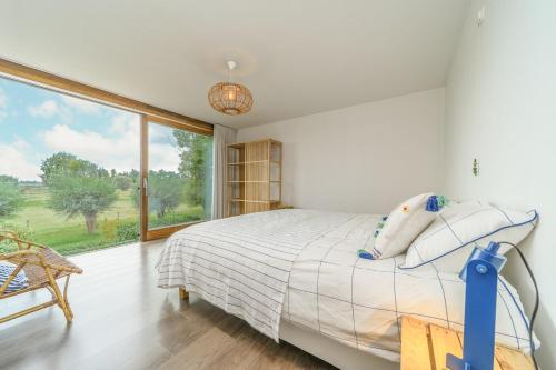 a bedroom with a bed and a large window at Stormhus - Oostduinkerke in Koksijde