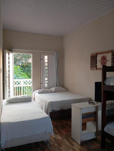 a bedroom with two beds and a window with a porch at Pousada Riocabana in Barreirinhas