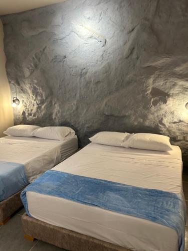 two beds in a room with a stone wall at Hotel Kyros by 70 in Medellín