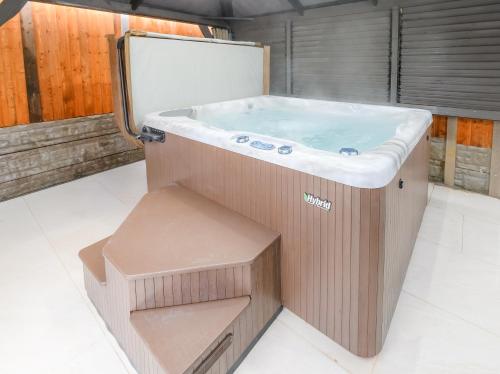 a wooden bath tub with a bench in a bathroom at Hot Tub Hideaway, Private Retreat in Walsall