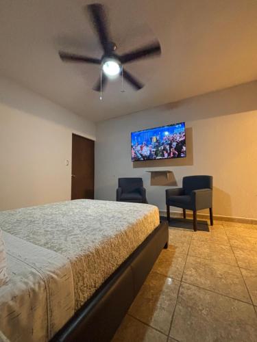 a bedroom with a bed and two chairs and a flat screen tv at Habitación Roble, cómoda y espaciosa in Saltillo