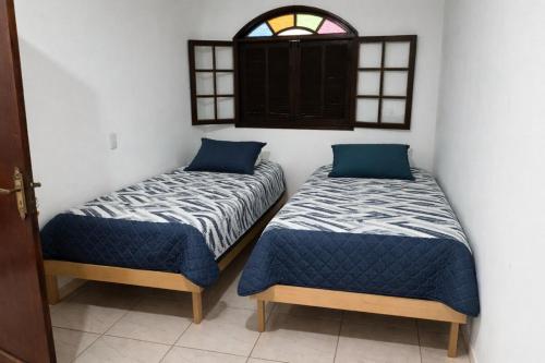 two beds in a room with a window at Duque de Caxias Apartmento in Duque de Caxias
