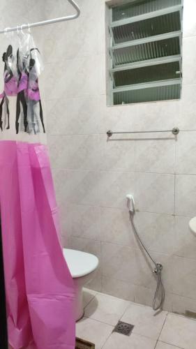 a bathroom with a pink shower curtain and a toilet at Duque de Caxias Apartmento in Duque de Caxias