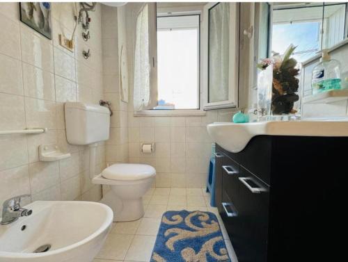 a bathroom with a sink and a toilet and a window at Casa vacanza "Orchidea" in Marzamemi