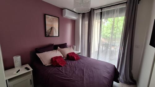 a bedroom with a bed with red pillows and a window at La Valiette in La Seyne-sur-Mer