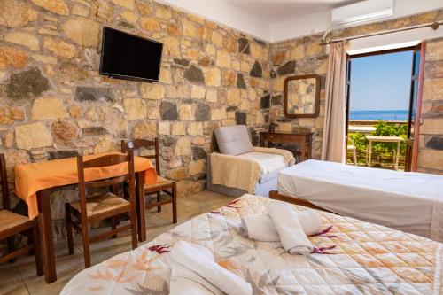 a room with two beds and a tv on a stone wall at Maria Apartments in Amoopi