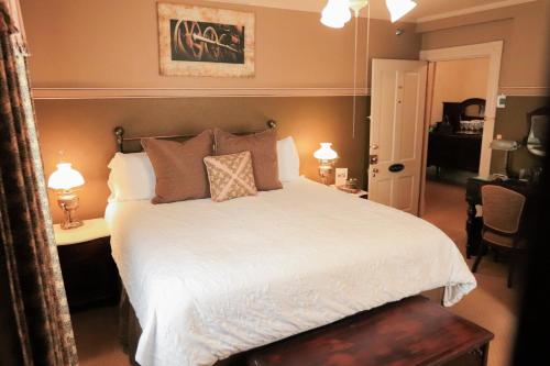 a bedroom with a bed with white sheets and pillows at The Russell Room at The Historic Eureka Inn and Event Center in Jonesborough