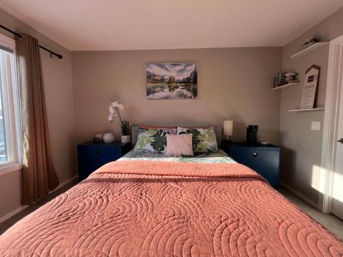 a bedroom with a large bed with a orange blanket at Sunlit Haven in Calgary