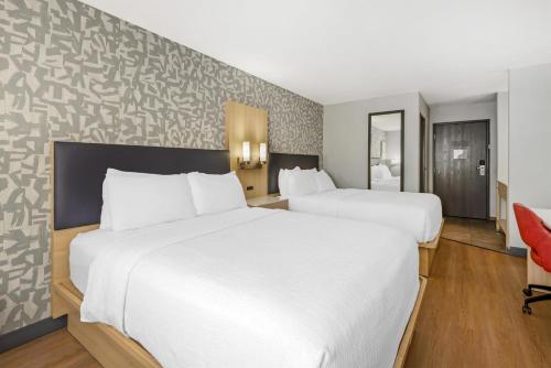 two beds in a hotel room with white sheets at Best Western Montrose Inn in Montrose