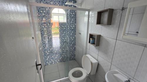 a white bathroom with a toilet and a sink at Casa da vó cida in Itapoa
