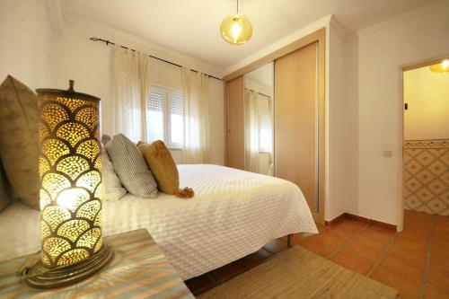 a bedroom with a bed and a lamp on a table at Apartamento Azur in Vila Nova de Milfontes