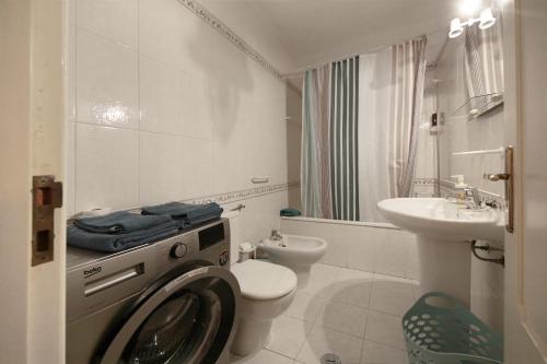 a bathroom with a washing machine and a sink at Apartamento Azur in Vila Nova de Milfontes