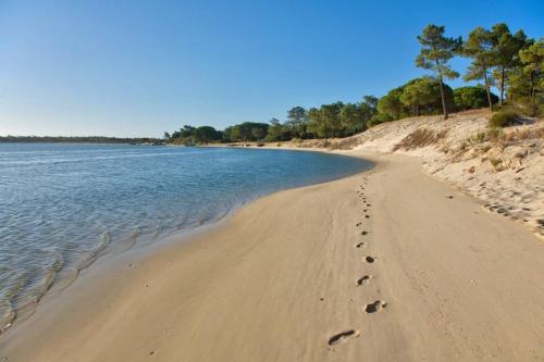 a beach with footprints in the sand and water at Luxury Tróia T1 Pool, Sauna Parking in Troia