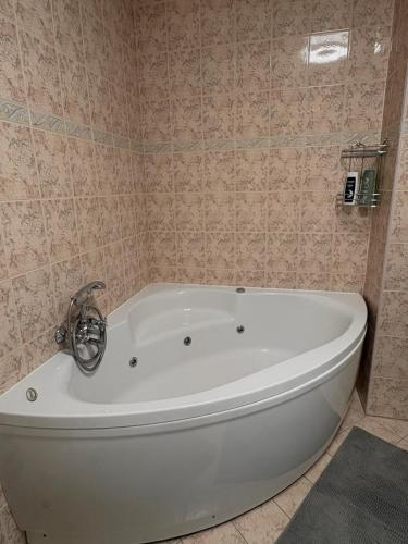 a white bath tub in a bathroom with pink tiles at Apartment OrMarić in Otočac