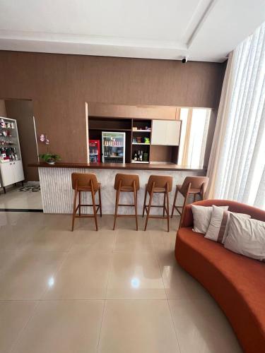 a living room with a couch and a bar with stools at HOTEL PLAZA PONTES e LACERDA in Pontes e Lacerda