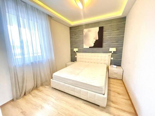 a bedroom with a white bed and a window at Paris Garden Rooms in Debrecen