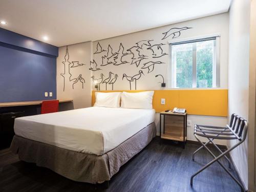 a bedroom with a bed and a wall with birds on it at ibis Styles Belem Nazare in Belém