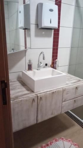 a bathroom with a white sink and a mirror at Chalé da Janete in Capão da Canoa