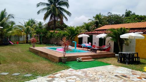 a backyard with a pool with a table and chairs at Chalé a beira mar ilhéus in Ilhéus