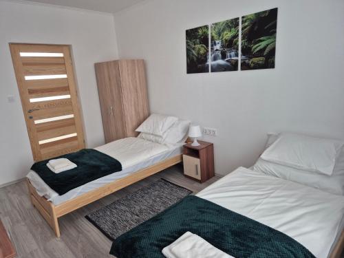 a bedroom with two beds and a night stand at Leander Apartman in Gyömrő
