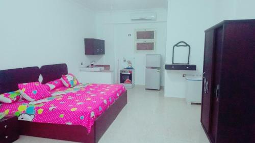 a bedroom with a pink bed and a refrigerator at Grand Plaza Apartment in Marsa Alam City