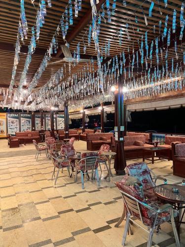 a dining room with tables and chairs and chandeliers at Grand Plaza Apartment in Marsa Alam City