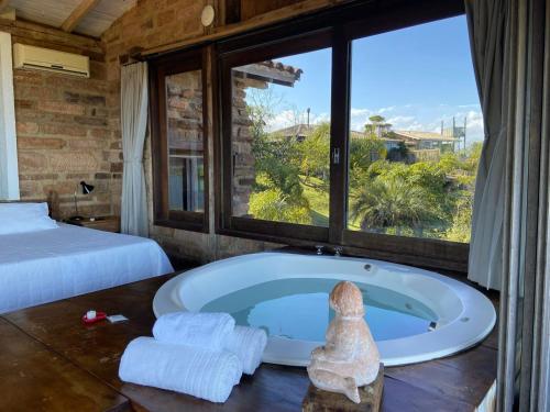 a bath tub in a room with a large window at Hospedaria Ponta da Piteira in Imbituba
