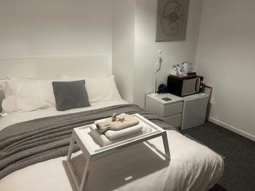 a bedroom with a bed with a table on it at fAiRy DeLL Guesthouse 24-7 check in, cozy lockable rooms, tv, tea tray with choccies, cooling fans, free wifi and parking, COA, all are welcome in Bradford
