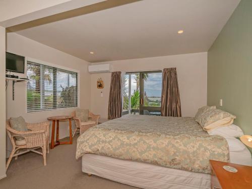 a bedroom with a bed and a large window at The Harbour View Tairua in Tairua
