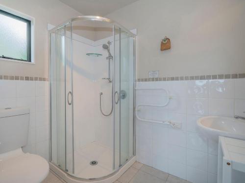 a bathroom with a shower and a toilet and a sink at The Harbour View Tairua in Tairua