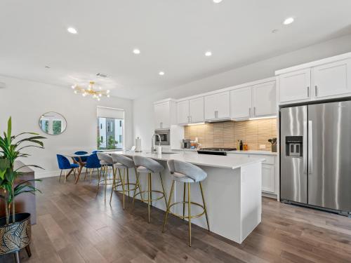 a kitchen with white cabinets and bar stools at Modern Dallas Townhome with Private Rooftop, City View, Private Parking & Grill in Dallas